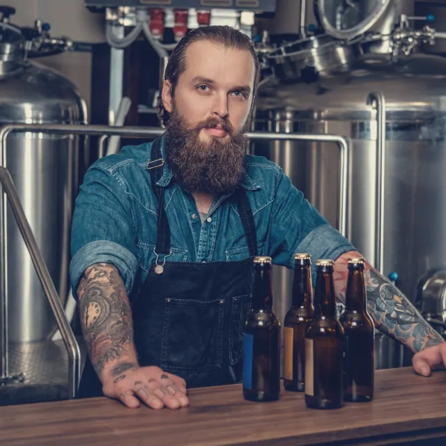 Hersteller in seiner Brauerei neben fertigen Produkten